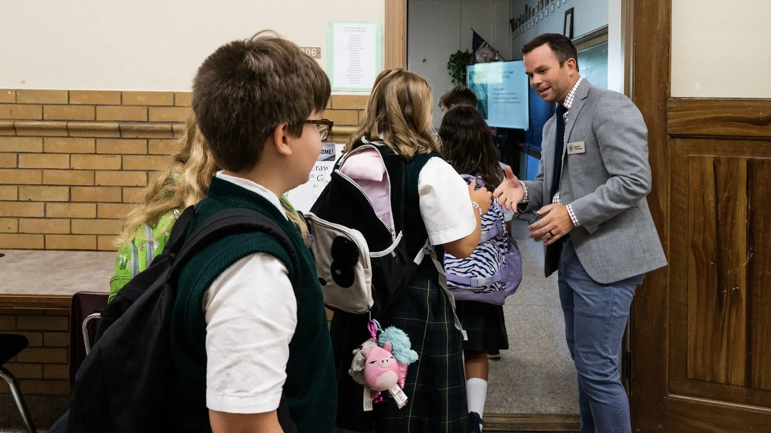 A teacher greets students as they enter class in the morning